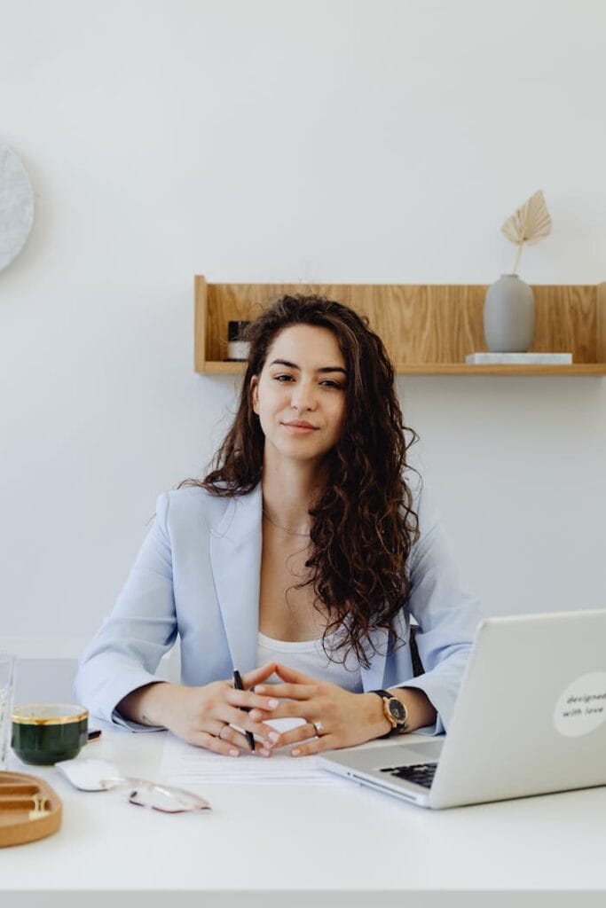 pexels-photo-8528744 Portrait of a confident businesswoman sitting at a desk with a laptop in a modern office.